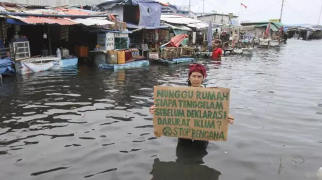 Aktivis lingkungan memprotes dampak perubahan iklim di tengah banjir rob di kawasan Muara Angke, Jakarta Utara pada Selasa, 7 Desember 2021.