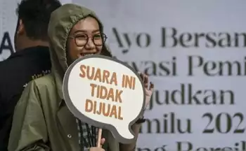 Warga menunjukan tulisan penolakan politik uang saat Bawaslu On Car Free Day