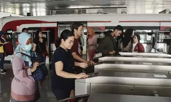 Penumpang melakukan pemindaian (tapping) kartu usai naik kereta LRT (Light Rail Transit)