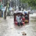 Warga berkendara melewati jalan yang banjir setelah hujan lebat di Guwahati, India