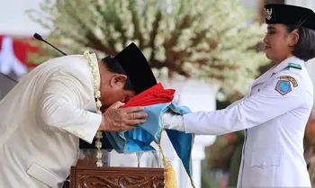 Presiden Prabowo Subianto (kiri) mencium duplikat Bendera Merah Putih saat diserahkan kepada Paskibraka pembawa baki Bianca Alessia Christabella