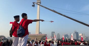 Masyarakat bersiap menyaksikan prosesi kirab bendera Merah Putih di depan pintu Cawan Monas sisi Utara, Jakarta Pusat, Minggu (17/8/2025).